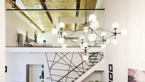 A spacious interior with a wooden floor, a modern staircase, a sectional sofa, and a dining area. - Aigli Seafront Loft-luxury Design Retreat (Kalamata)