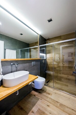 Une salle de bain moderne avec un meuble-lavabo en bois, un lavabo blanc, une cabine de douche en verre et un miroir au-dessus du lavabo.