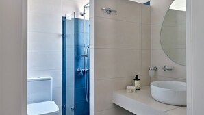Une salle de bain moderne comprenant des toilettes, un espace douche et un meuble-lavabo avec un lavabo et un miroir.