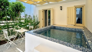 Un espace piscine extérieur moderne, doté d’un sol carrelé, d’une table blanche avec des chaises et d’une pergola jaune au-dessus.