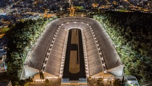 A large, modern stadium with a central track and surrounding seating areas, surrounded by dense urban buildings and greenery. - The Urban Loft 2 - Athens Unique Oasis (Kaisariani)