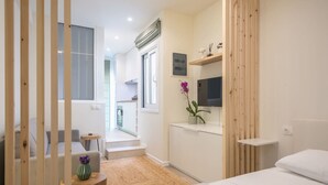 A modern hotel room with a bed, a small table with a vase, a TV on the wall, and a view of the outside balcony. - The Urban Loft 2 - Athens Unique Oasis (Kaisariani)