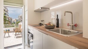 A modern kitchen with a wooden countertop, stainless steel sink, and a view of a balcony with outdoor furniture. - The Urban Loft 2 - Athens Unique Oasis (Kaisariani)
