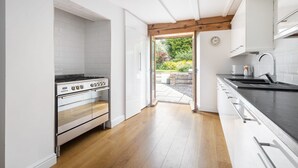 A modern kitchen with white cabinetry, a stainless steel stove, and a wooden floor. - Host Stay Sunnyside Barn (Bridlington)