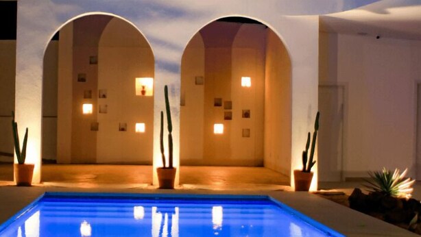 A pool area with a blue pool, arched walkways, and potted plants. - Roka Hotel Boutique (Boa Vista)