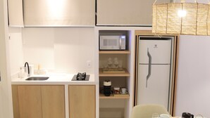 A compact kitchen with a microwave, coffee maker, and wine glasses on shelves. - Roka Hotel Boutique (Boa Vista)