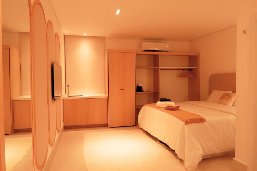 Une chambre à coucher avec un lit, une armoire, un miroir et un téléviseur.