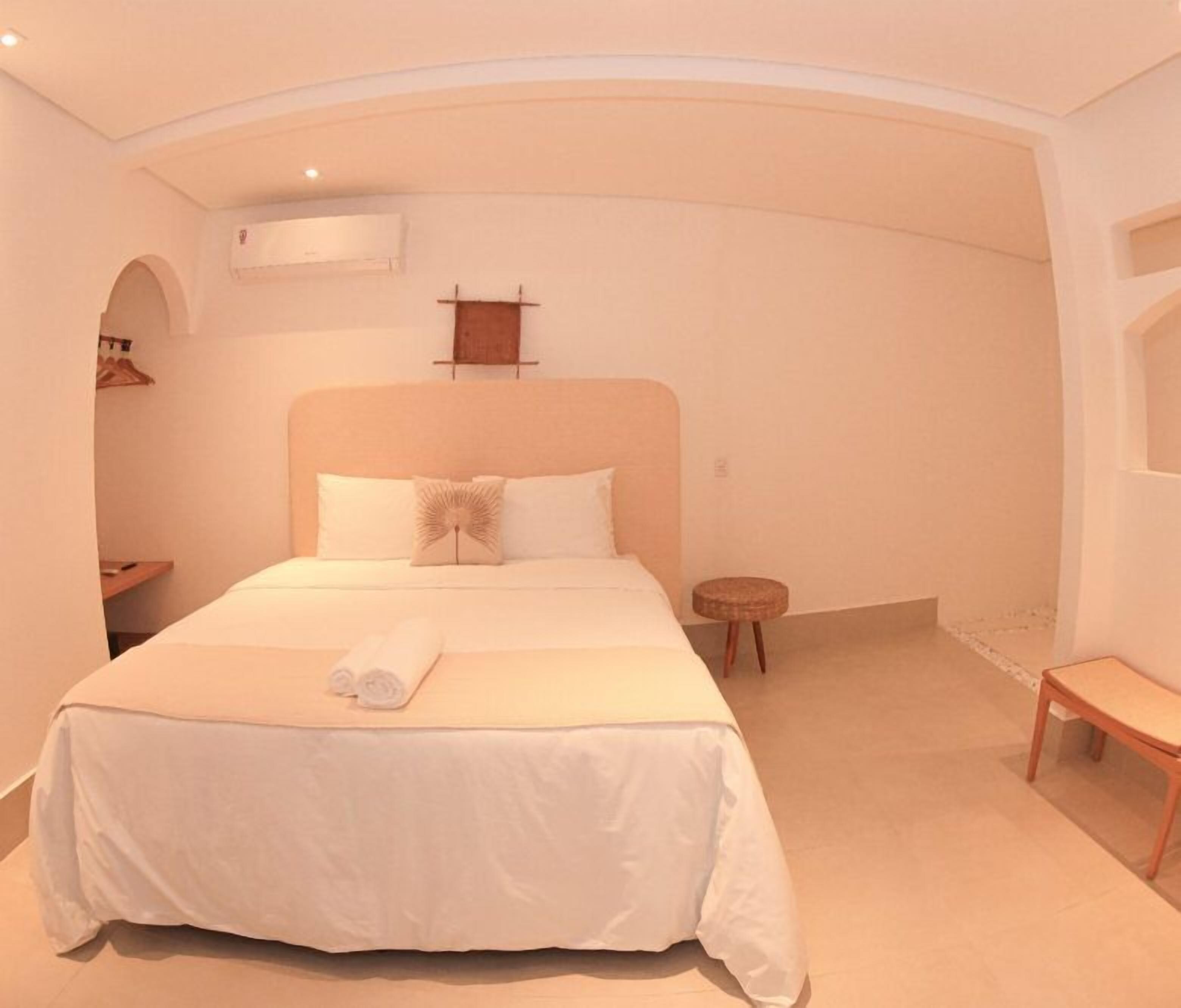 Ein Hotelzimmer mit einem großen Bett, einem kleinen runden Tisch und einer Bank.