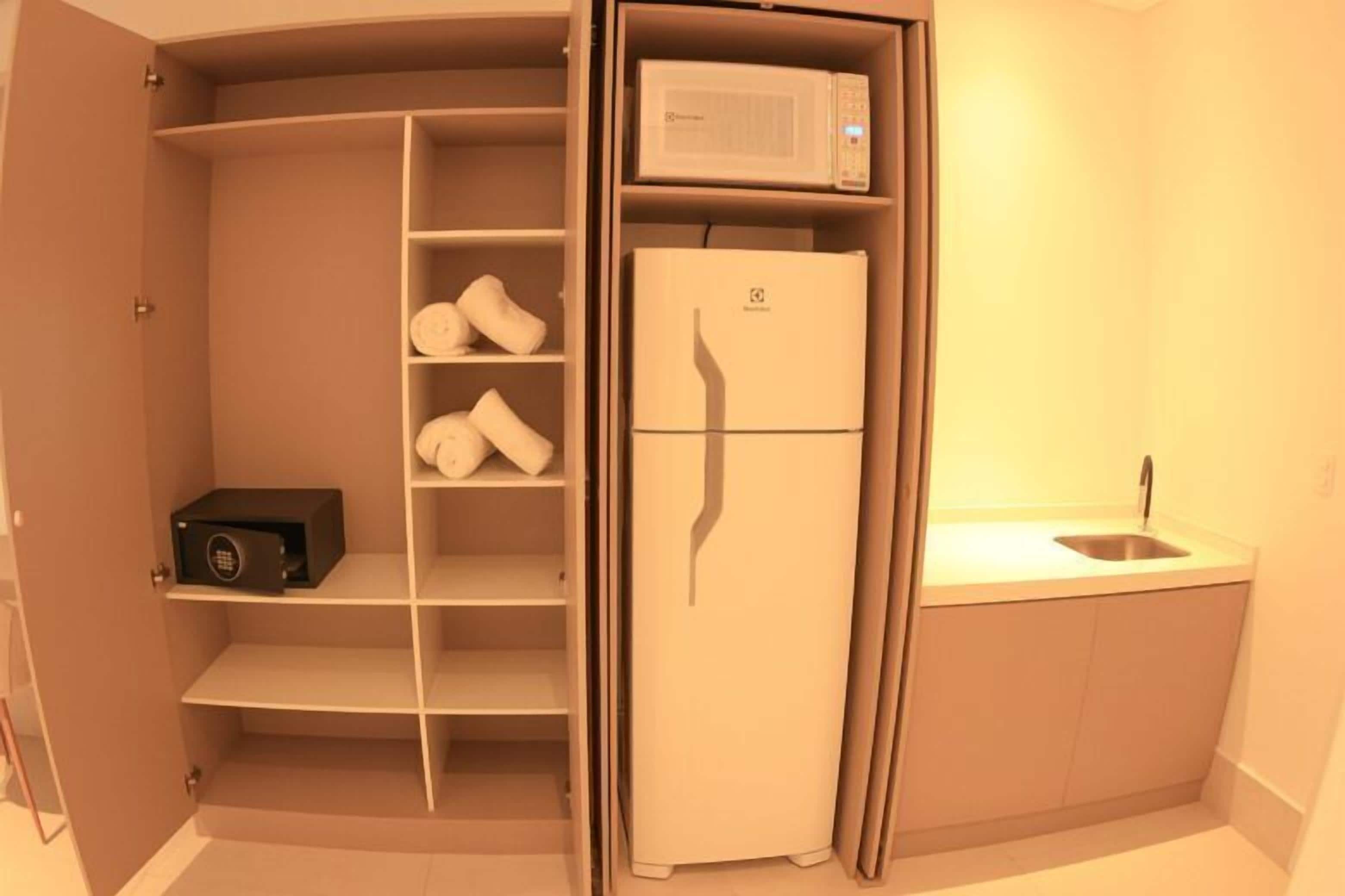 Une cuisine compacte équipée d’un four à micro-ondes encastré, d’un réfrigérateur et d’un évier.