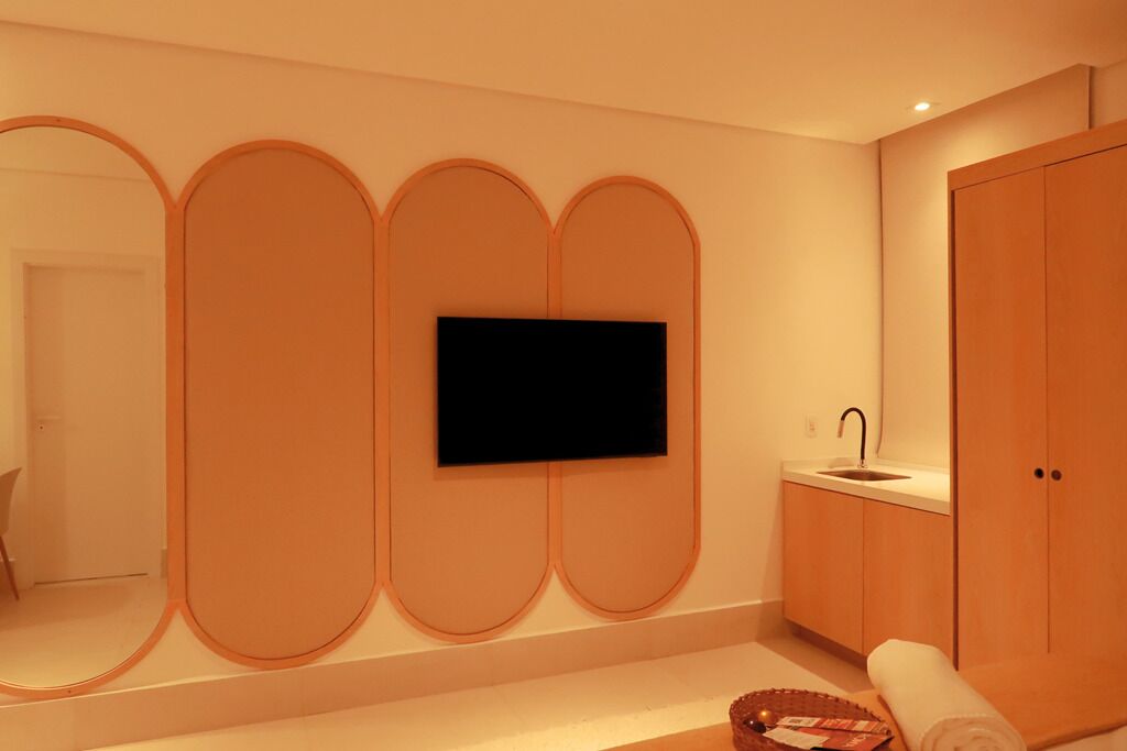 Un baño moderno con un televisor de pantalla plana montado en la pared, armarios de madera y un lavabo.