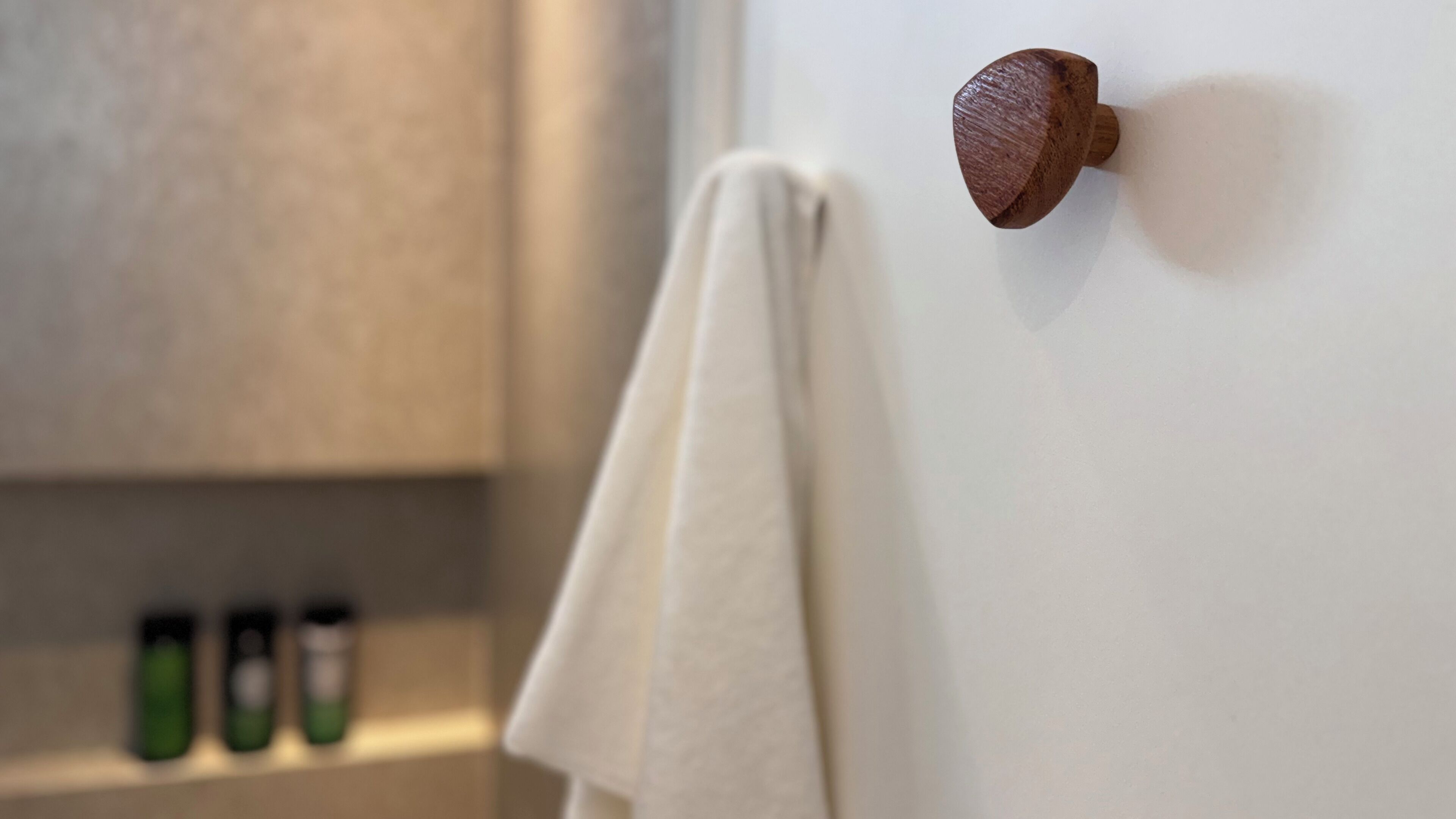 A bathroom with a wooden door knob, a towel hanging on the wall, and a shelf with toiletries.