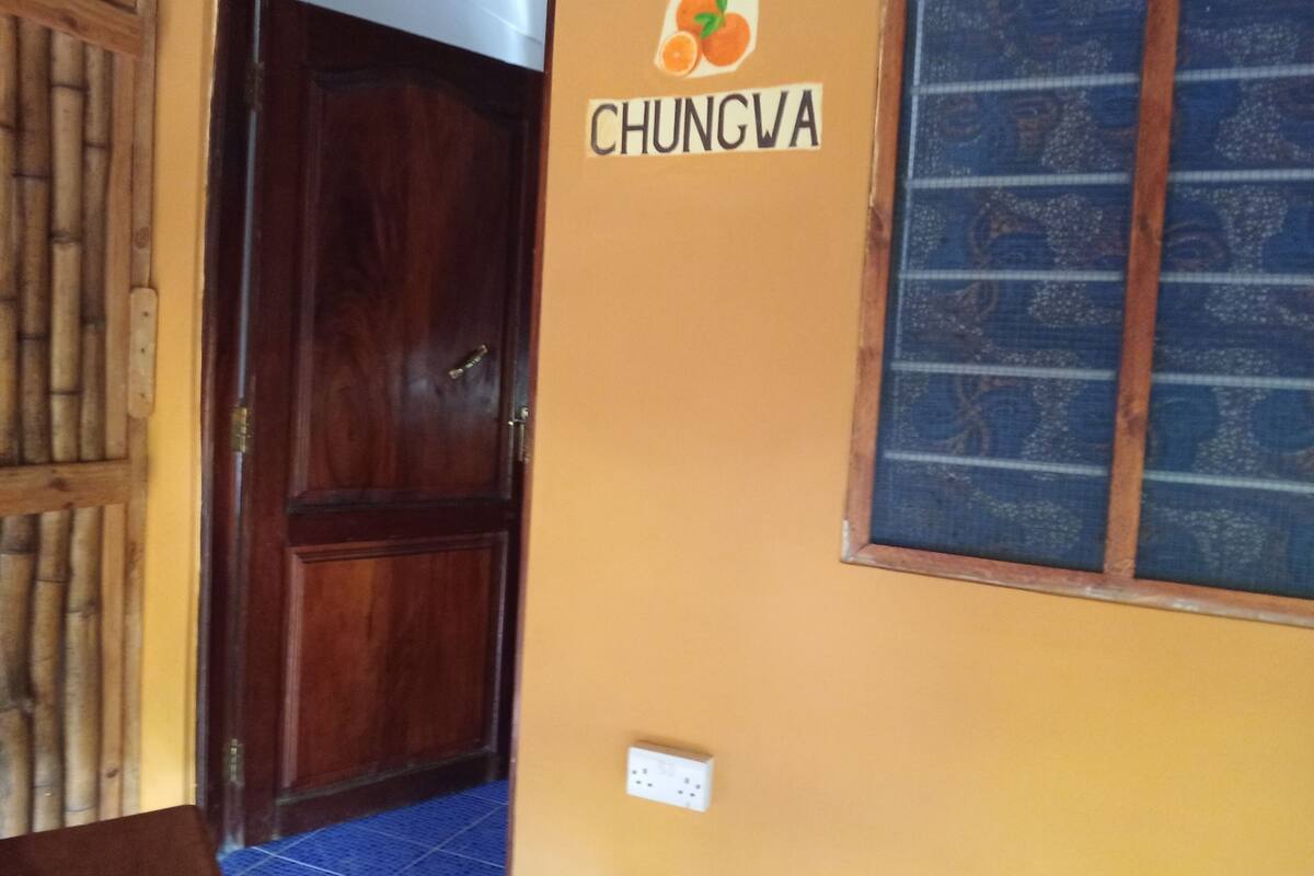 Una puerta de madera, una pared con un cartel que dice "CHUNGVA" y un ventanal con diseño.