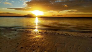 Una playa con un atardecer sobre el océano.
