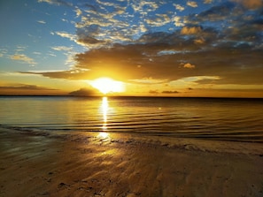 Una playa con un atardecer sobre el océano.