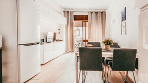 A modern kitchen with white appliances, a dining area with a table and chairs, and a view into the living area.