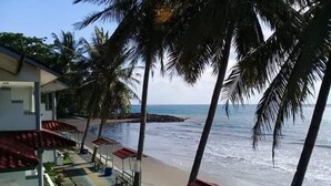 A beachside hotel with a pool area, palm trees, and a view of the ocean. - Resort Prima Anyer (Cinangka)