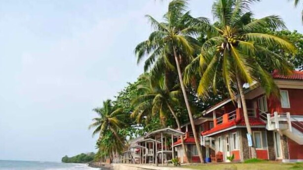 A beachfront hotel with multiple-story buildings, palm trees, and a stone wall along the beach. - Resort Prima Anyer (Cinangka)