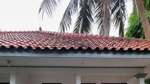 A two-story building with a tiled roof and a covered porch. There are two visible doors, one with a glass panel and another with a wooden door. The building has a white exterior with a stone base. - Resort Prima Anyer (Cinangka)