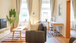 A cozy living room with a sofa, a small table, a TV, and a plant. - Cosy & quiet apartment w/great transport links (Erfurt)