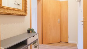 A hallway with a wooden door, a mirror with a gold frame, and a small plant on a console table. - Cosy & quiet apartment w/great transport links (Erfurt)