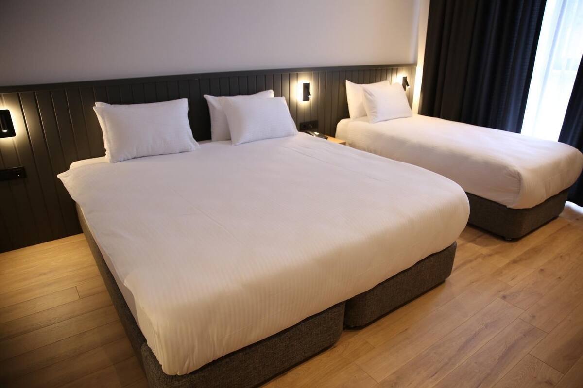 A hotel room with a large bed, a smaller bed, and a nightstand.