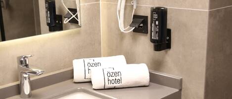Un baño de hotel con lavamanos, dispensador de toallas y secador de pelo montado en la pared.