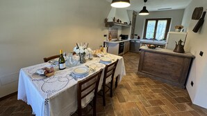 A dining area with a table set for four, a kitchen in the background, and a window with curtains. - Villa in Lucca with 3 bedrooms sleeps 7 (Lucca)
