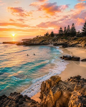Eine Küstenlandschaft mit felsigen Klippen, einem Sandstrand und einem Sonnenuntergang über dem Meer.
