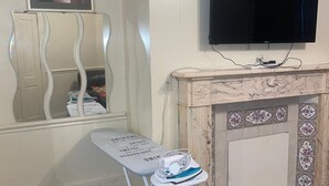 Ein Zimmer mit einem Flachbildfernseher über einem Kamin, einem Bügelbrett mit Bügeleisen und einem dekorativen Spiegel.