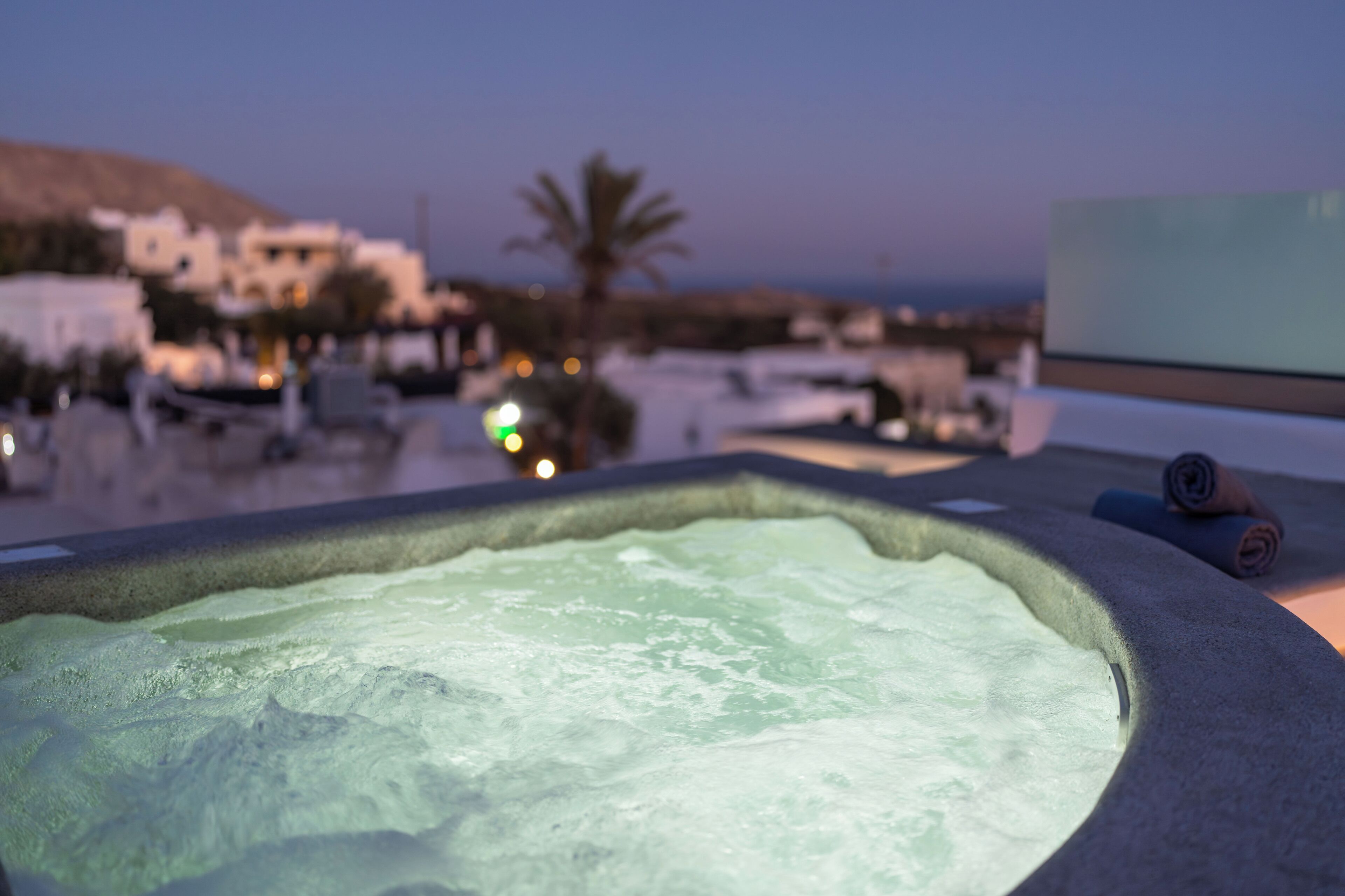 A hot tub with a view of a coastal town at dusk.