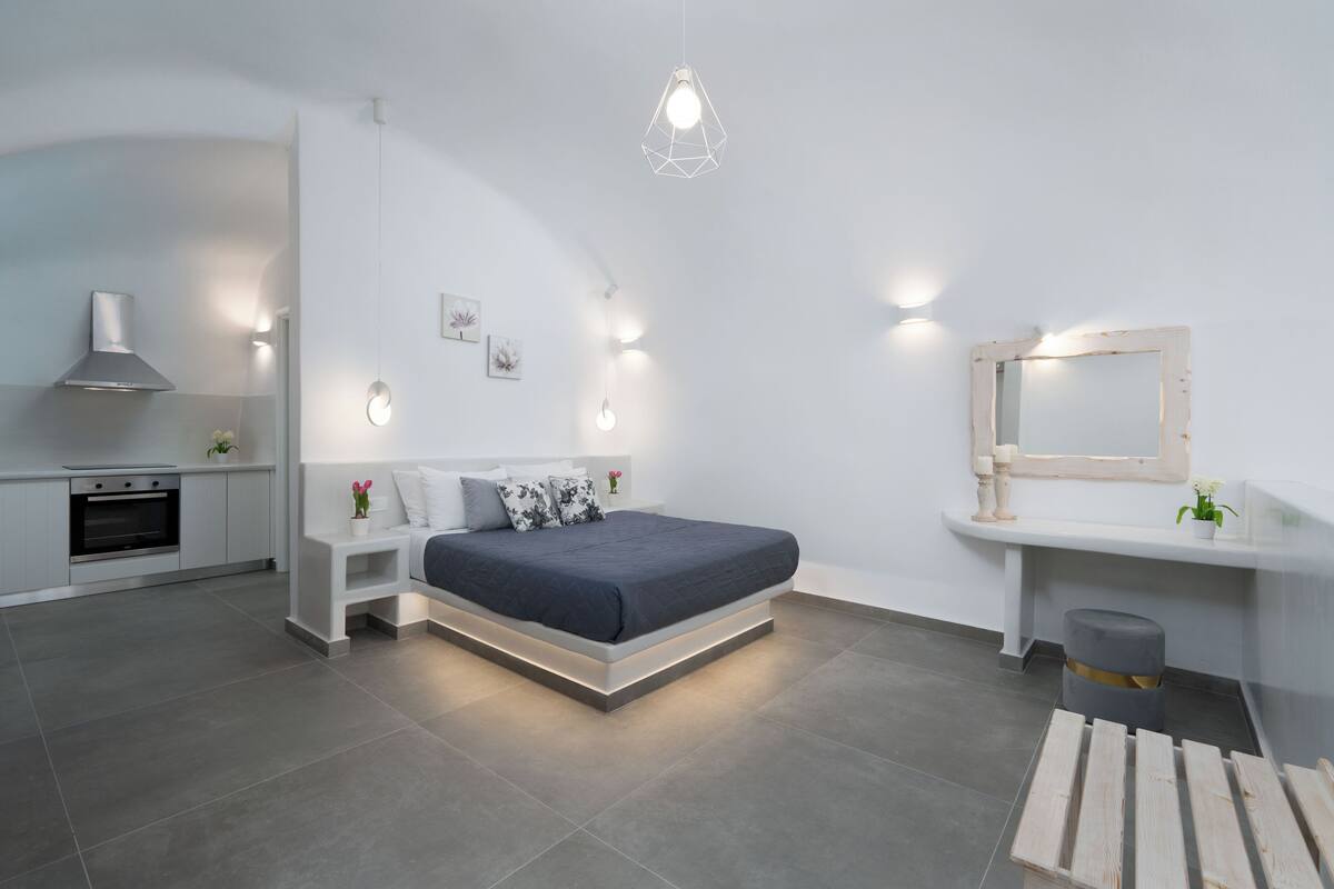 A modern bedroom with a bed, bedside tables, a mirror, and a small stool.