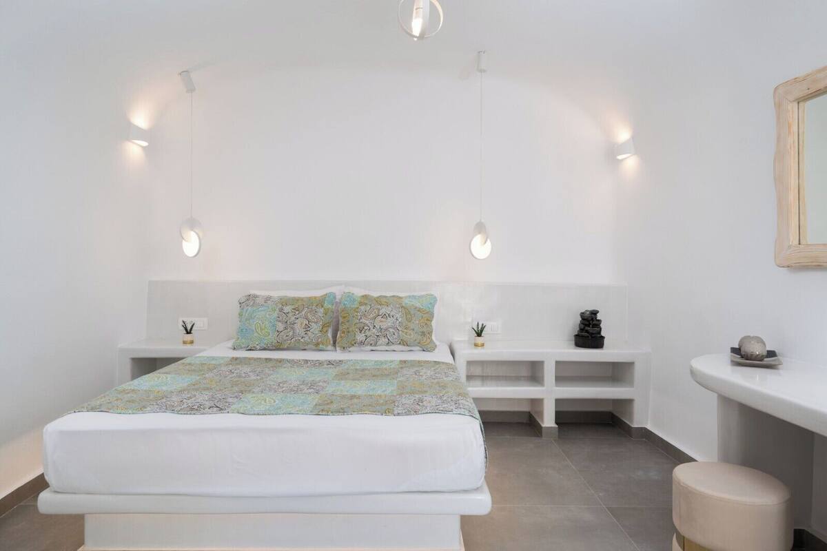 A modern bedroom with a large bed, bedside tables, and a small stool.