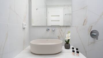 Ein modernes Badezimmer mit einem runden Waschbecken, einem Spiegel und einer Topf-Orchidee.
