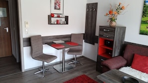 Una sala de estar moderna con comedor, con una paleta de colores rojo y gris, una chimenea y vistas a un jardín.