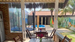 An outdoor patio with a table and chairs, a pool, and a mural on the wall. - Home Beach Mar (Aquiraz)