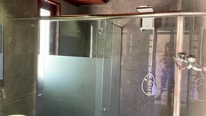 A modern bathroom with a glass-enclosed shower, a marble sink, and a wooden ceiling. - Home Beach Mar (Aquiraz)