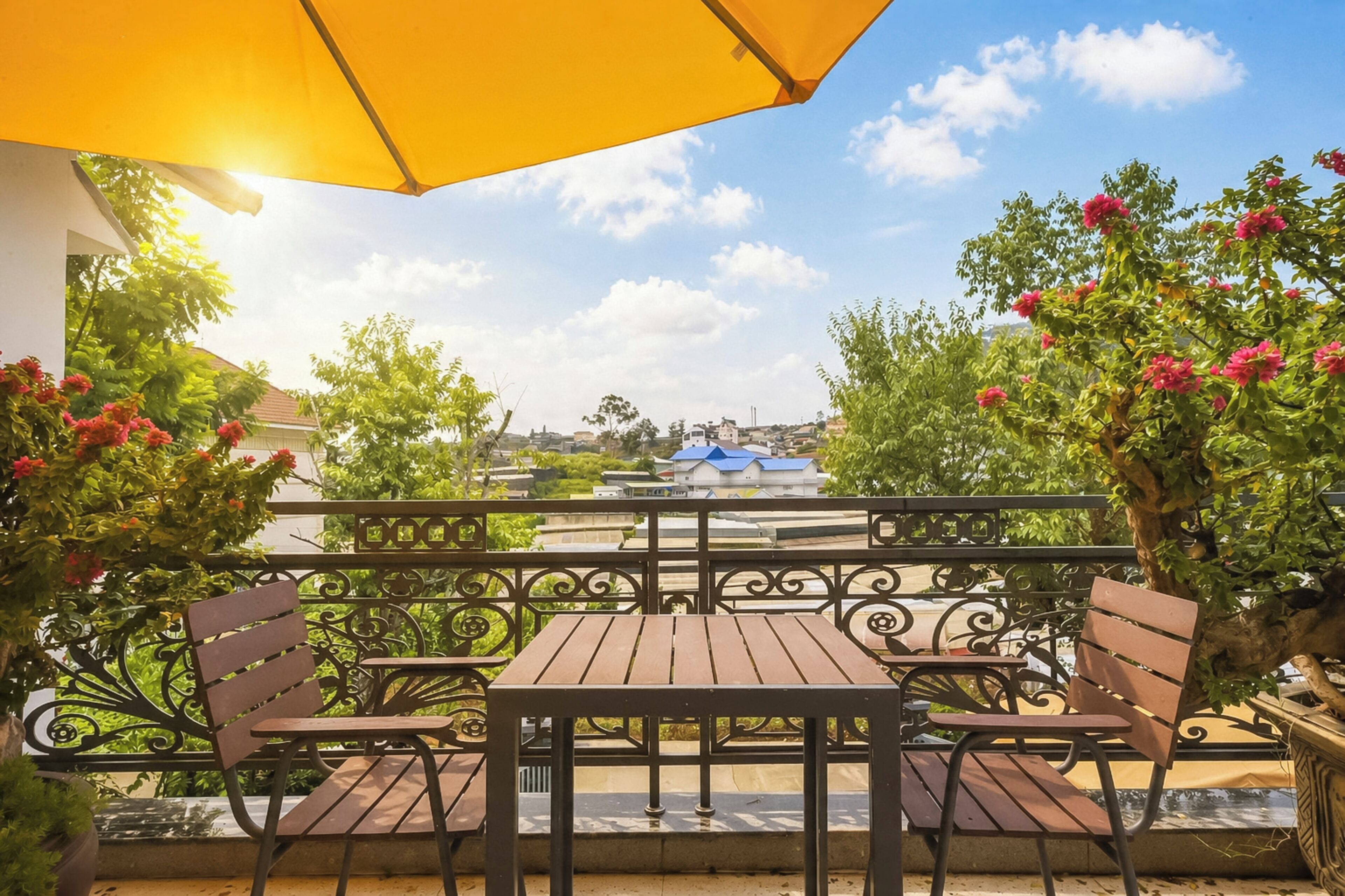 Un patio con mesa y sillas, rodeado de follaje y vistas a un pueblo lejano.