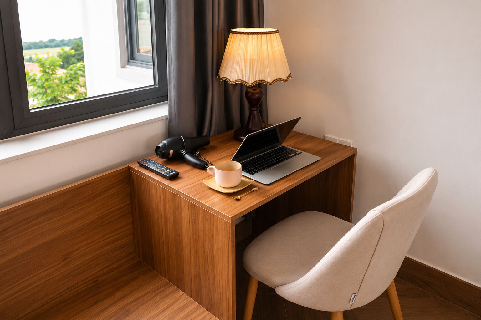 Ein Holztisch mit einem Laptop, einer Fernbedienung, einem Haartrockner und einer Kaffeetasse.