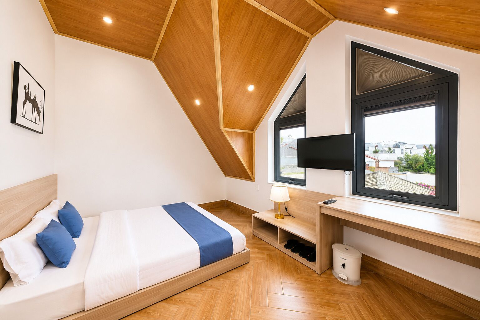 A modern bedroom with a bed, a desk, a TV, and a window with a view.