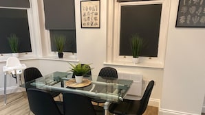 A modern dining area with a glass table, black chairs, and potted plants. - Cozy Coastal Retreat in Bournemouth (Bournemouth)