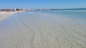 A beach with clear shallow water, a sandy shore, and buildings in the background. - Sarasota Resort Home Pool Golf Beach Siesta Key St. Armands Downtown Pickleball (Sarasota)