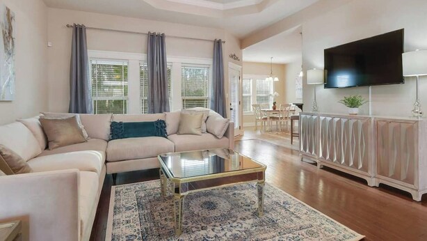 A spacious living room with a sofa, coffee table, and a television mounted on the wall. - Spacious 3BR Condo in Ocean Springs (Vancleave)