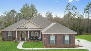 A two-story house with a front porch, brick exterior, and a well-maintained lawn. - Spacious 3BR Condo in Ocean Springs (Vancleave)