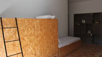 Une chambre avec un lit superposé, une échelle, une petite table de chevet et une armoire.
