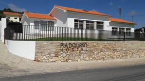 A two-story building with a stone wall and a metal fence. - Hostel Pia do Urso (Batalha)