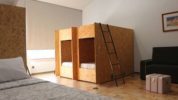 A room with a bunk bed made of wood, a ladder, a suitcase, and a black chair.
