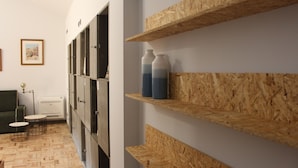 A hallway with wooden shelves, a green sofa, and a small table with a lamp. - Hostel Pia do Urso (Batalha)