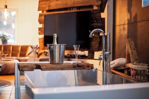 Relax in a spacious bathroom with a large bathtub, glass-enclosed shower, and a wooden shelf.
