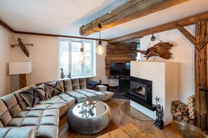 Relax in this inviting living space with a large L-shaped sofa, fireplace, and wall-mounted TV.