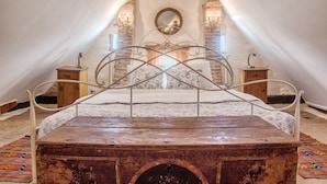 A bedroom with a large bed, a wooden chest, and a mirror on the wall. - Dominic Boutique  (Saschiz)